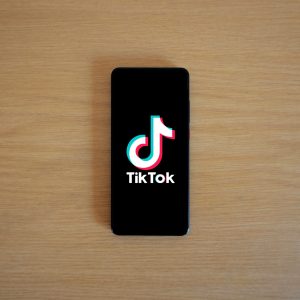 Smartphone with TikTok app displayed on black screen against a wooden background.