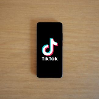 Smartphone with TikTok app displayed on black screen against a wooden background.